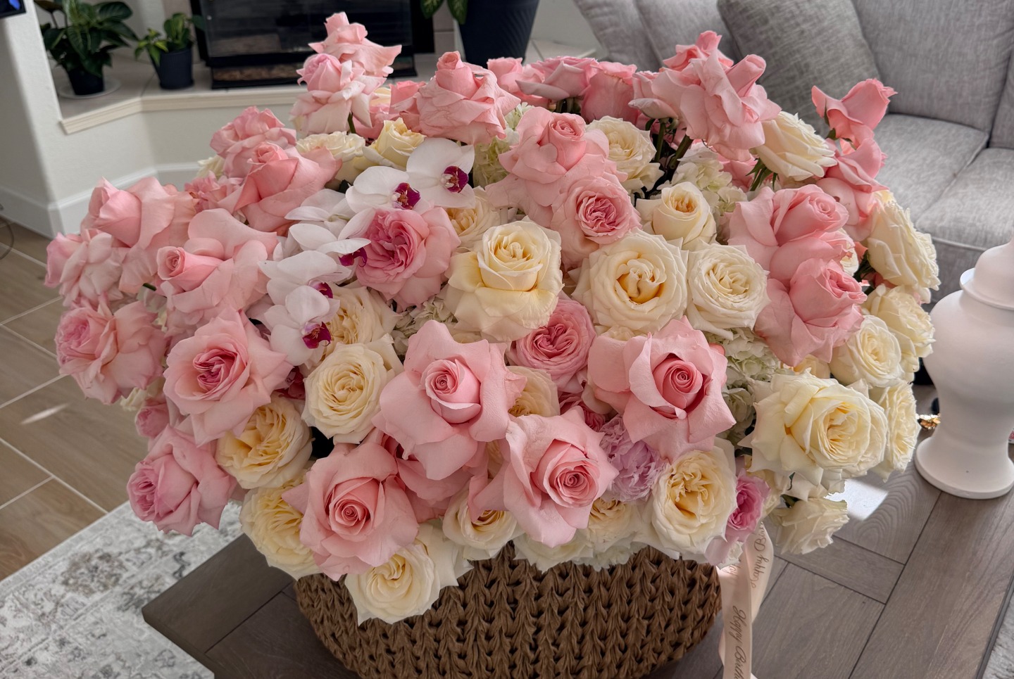 Lush pink and cream roses in a woven basket with a Happy Birthday ribbon